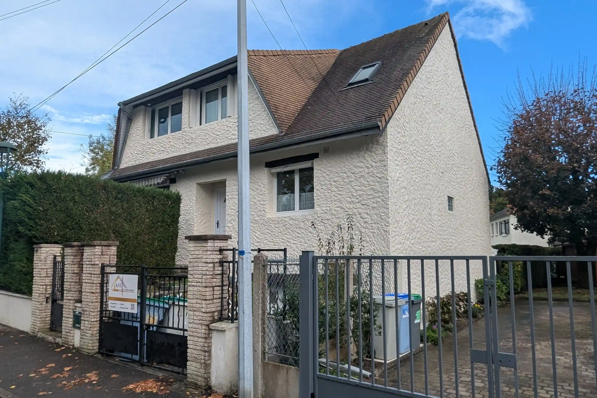 Vue d'ensemble de la maison depuis la rue, montrant la façade latérale rénovée en blanc aux Essarts-le-Roi